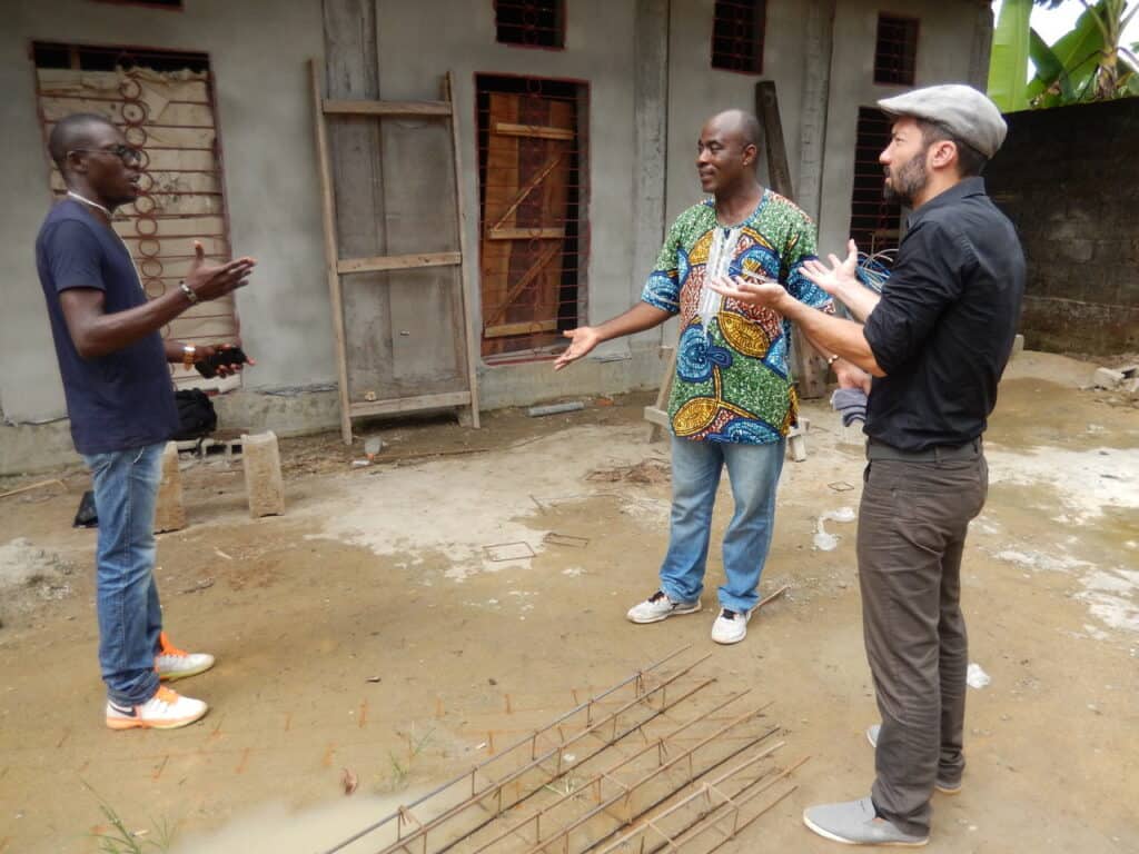 Akos Lukacs diskutiert mit zwei anderen Personen vor dem zukünftigen Gesundheitszentrum in Bekoko.