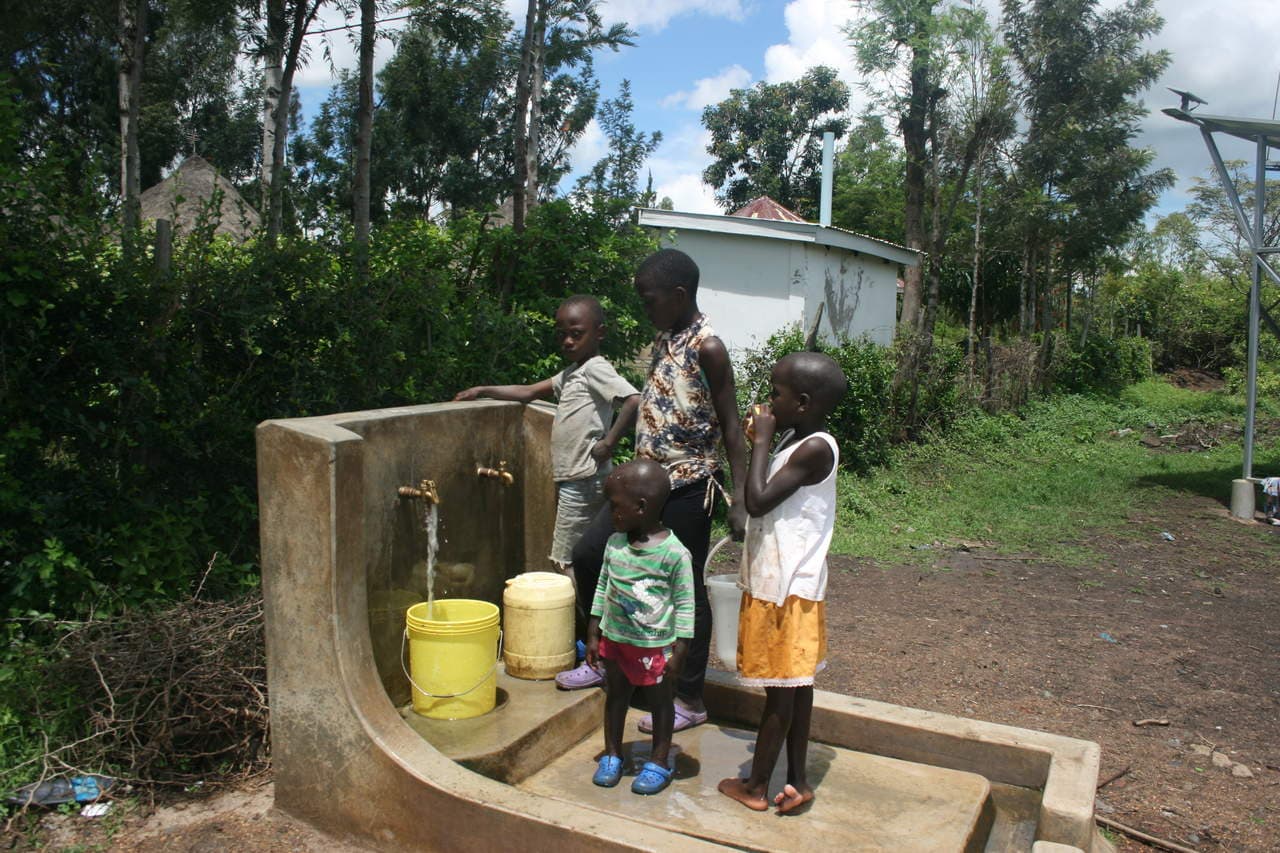Kinder holen aus dem Brunnen frisches Wasser. Ermöglicht wird dies durch den Solar-Wasser-Kiosk.