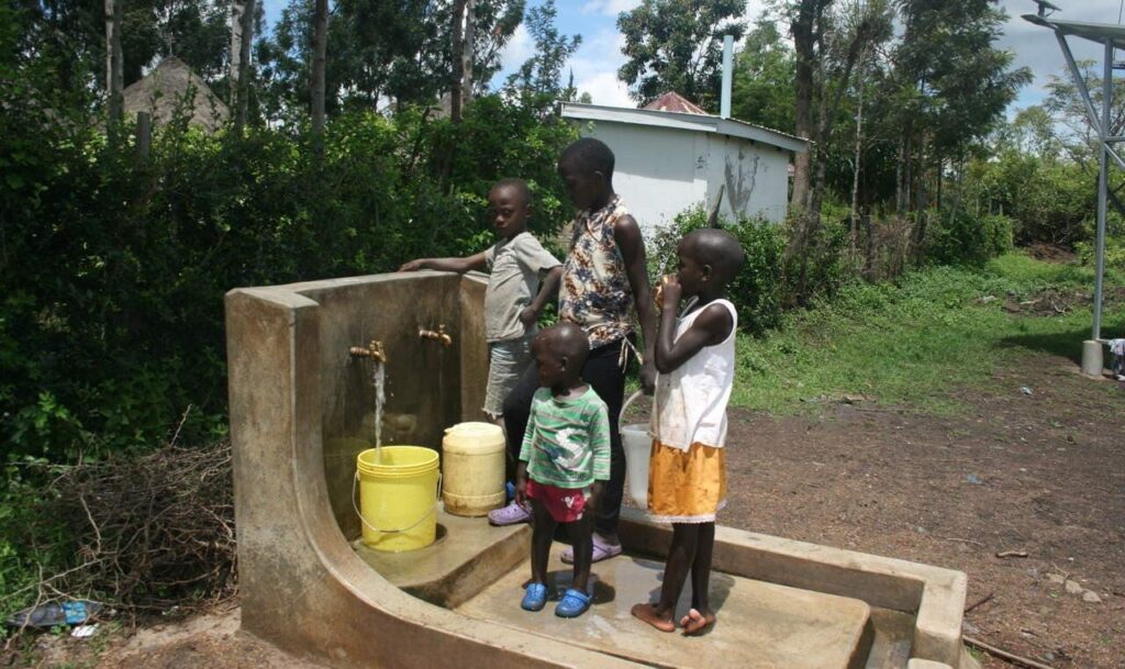 Kinder holen aus dem Brunnen frisches Wasser. Ermöglicht wird dies durch den Solar-Wasser-Kiosk.