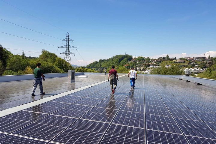 Personen auf einem Dach mit einer grossflächigen Solaranlage